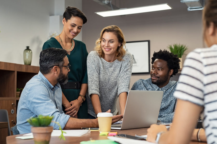 Colleagues discuss work around a laptop